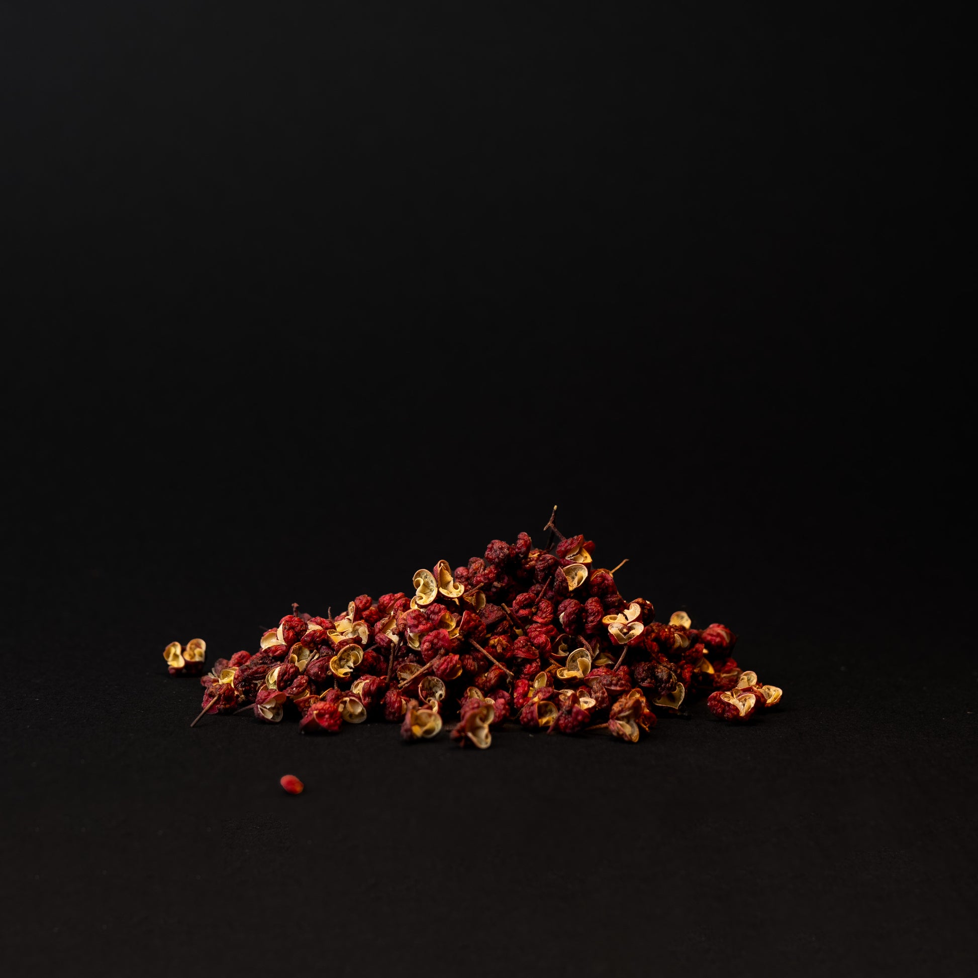 A small pile of red Sichuan peppercorns on a dark background.