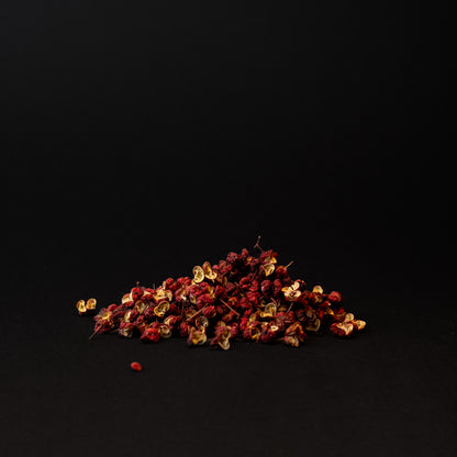 A small pile of red Sichuan peppercorns on a dark background.