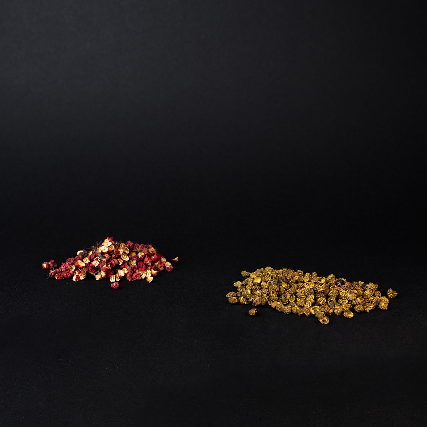A pile of red and green Sichuan peppercorns on a black background.  