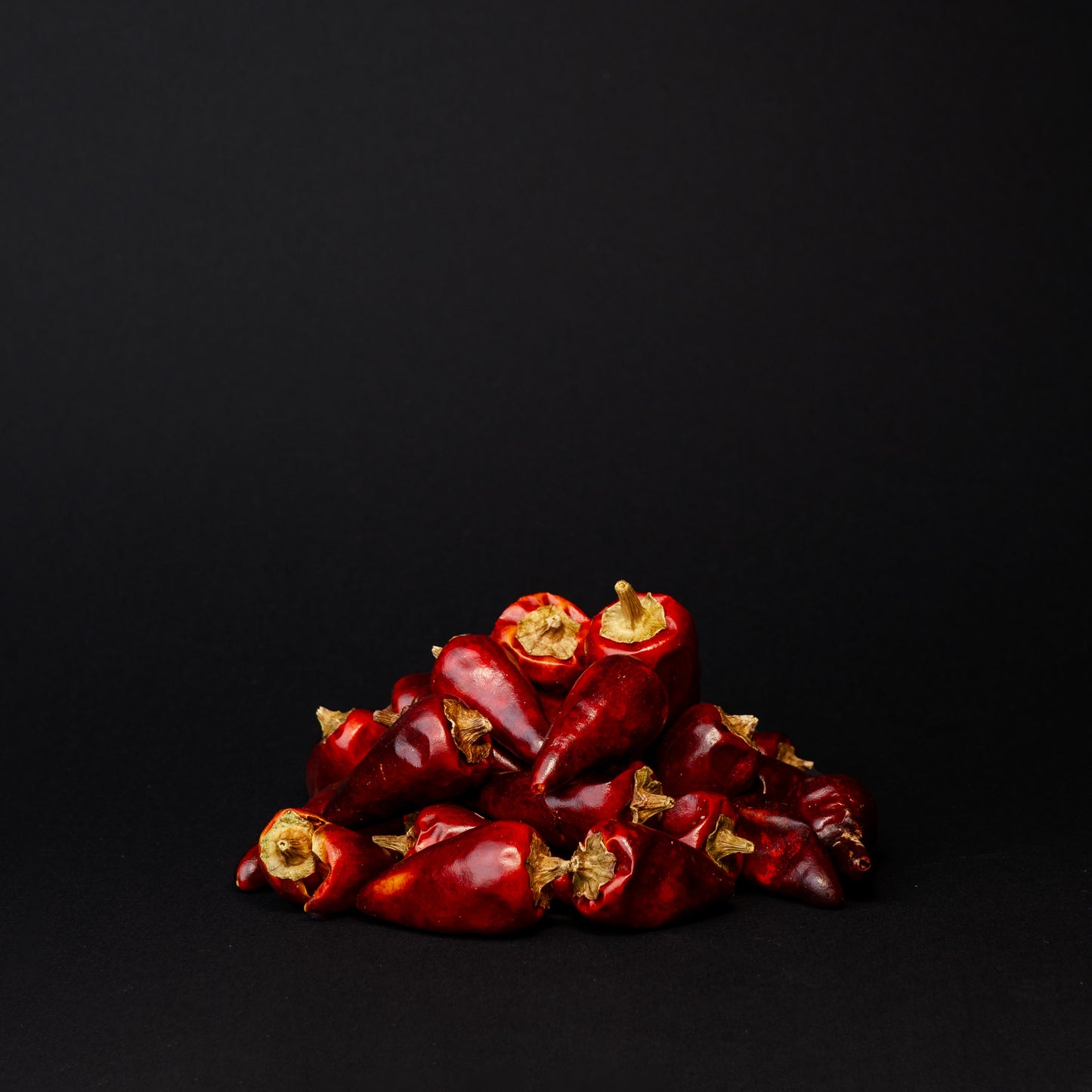 A pile of zi dan tou chili peppers on a black background. 