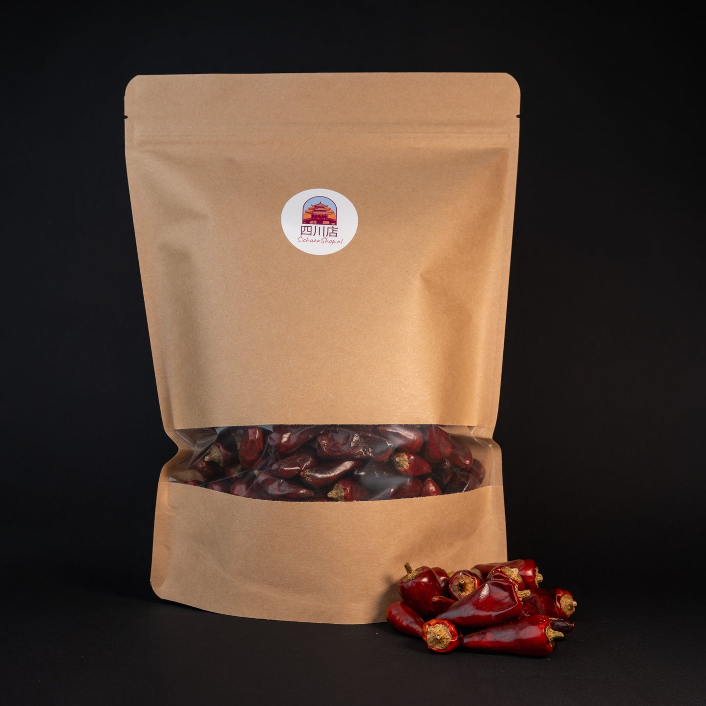 A brown package with zi dan tou chili peppers and a small pile of zi dan tou chilies in front of the package. 